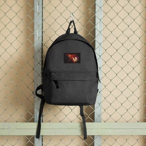 May include: A dark grey backpack with a black zipper and adjustable straps. The backpack features a colourful abstract design on the front.