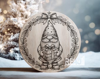 May include: A round wooden Christmas decoration featuring a gnome holding a gift. The gnome is surrounded by a holly wreath and a bow at the top. The design is etched into the wood, creating a rustic, festive look.