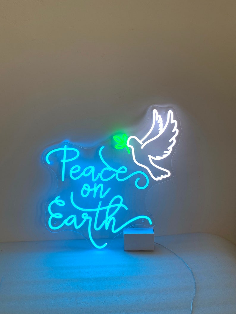 May include: A neon sign with a white dove holding an olive branch in its beak. The sign says "Peace on Earth" in a blue neon font.