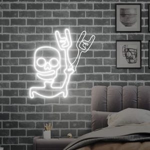 May include: White neon sign of a skeleton with a skull head making the rock and roll hand gesture. The sign is mounted on a brick wall.