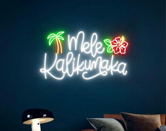 Op de afbeelding: Een wit neonbord met de tekst "Mele Kalikumaka" in een cursief schrift. Het bord bevat ook een groene palmboom en een rode hibiscusbloem.