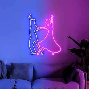 Puede incluir: Un letrero de neón que representa a una pareja bailando. El contorno es rosa brillante y azul, montado en una pared sobre un sofá. El fondo cambia de azul a morado, creando un ambiente vibrante.