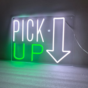 Puede incluir: Letrero de neón blanco con las palabras "PICK UP" en neón verde y una flecha blanca apuntando hacia abajo.