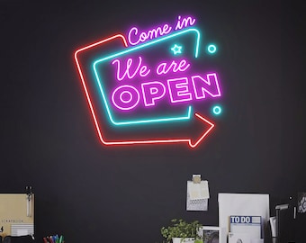 May include: Neon sign with a red and blue border and a pink interior. The sign says "Come in We are OPEN".