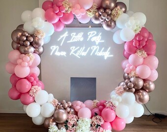 May include: A pink and white balloon arch with a neon sign that reads "A Little Party Never Killed Nobody". The arch is decorated with pink, white, and gold balloons.