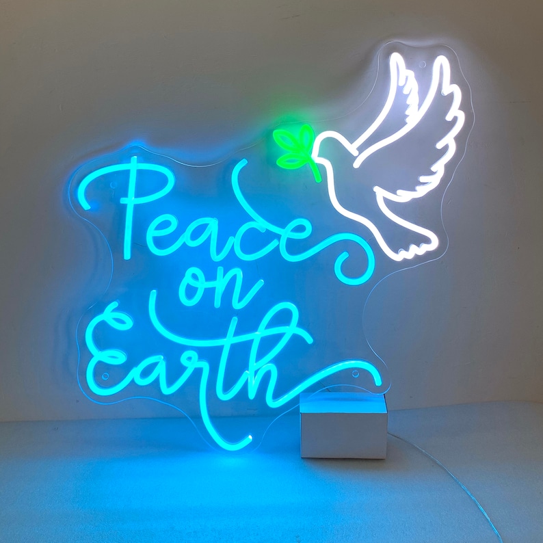 May include: A neon sign with a blue and green glow depicting a dove with an olive branch in its beak and the text "Peace on Earth".