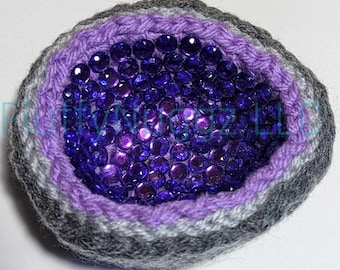 May include: A crocheted amethyst geode with a purple and gray striped exterior and a center filled with purple iridescent sequins.