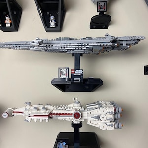 Puede incluir: Una colección de sets LEGO Star Wars expuestos en soportes negros. Los sets incluyen el Destructor Estelar Imperial, el Tantive IV y la Estrella de la Muerte. Los soportes tienen el logotipo de LEGO Star Wars y el nombre de la nave.