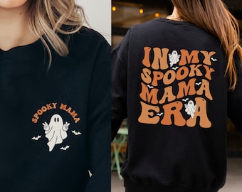 May include: Black sweatshirt with the text "Spooky Mama" and a ghost graphic on the front. The back of the sweatshirt features the phrase "In My Spooky Mama Era" with ghost and bat graphics in orange and white.