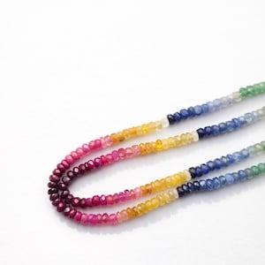 May include: Three strands of colorful gemstone beads. The beads transition through a spectrum of colors, including deep reds, pinks, yellows, blues, and greens. The faceted beads are strung together, creating a vibrant and eye-catching accessory.