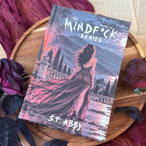 May include: A hardcover book titled The Mindf*ck Series Books 1-5 by S.T. Abby. The cover features an illustration of a person in a long dress standing on a balcony overlooking a landscape at dusk. Dark red roses are placed on the wooden surface.