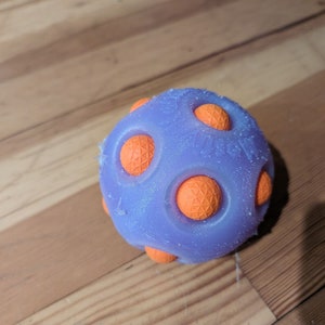 May include: A purple rubber dog toy with orange textured bumps. The toy is designed to be durable and fun for dogs to play with.