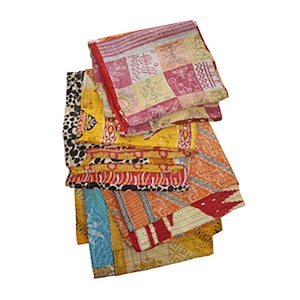 Könnte beinhalten: Ein Stapel bunter Kantha-Steppdecken mit verschiedenen Mustern und Designs, darunter geometrische Formen, florale Motive und Tierdrucke. Die Steppdecken werden aus recycelten Saris hergestellt und sind eine beliebte Wahl für die Wohnkultur und Geschenke.