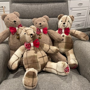 May include: Four plush teddy bears with red and white bandana-style bow ties. The bears are sitting on a gray couch.