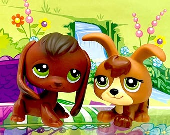 May include: Two brown and tan toy dachshund dogs with large green eyes. The toys are set against a backdrop of a green landscape with orange fruit and flowers. The toys are part of a larger playset.