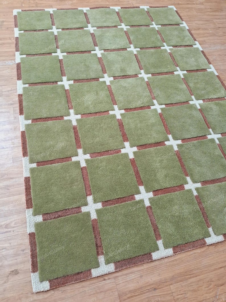 May include: A green and brown area rug with a geometric pattern. The rug has a grid pattern with squares of green and brown.