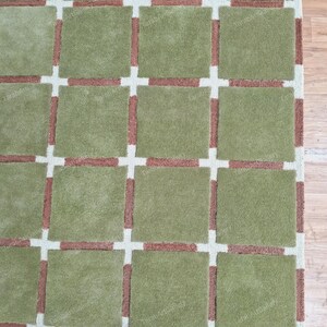 May include: A green and brown area rug with a grid pattern. The rug has a soft, plush texture.