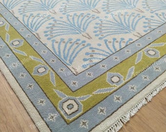 May include: A blue and green patterned rug with a fringe border. The rug has a floral design with a light blue background and a green border.