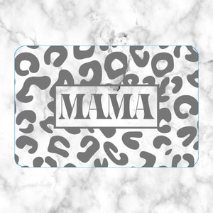 May include: A rectangular item with rounded corners, featuring a white marble background and gray leopard print spots. The word "MAMA" is displayed in a rectangular frame in the center.