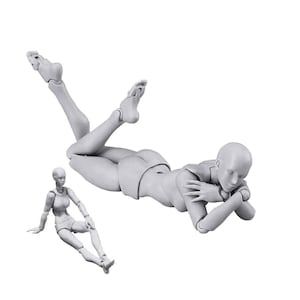 May include: Two gray articulated figures, one lying down with their head resting on their arm and the other sitting with their legs crossed. The figures are made of plastic and are used for drawing and sketching.