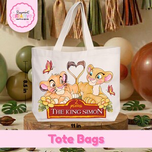 May include: A white tote bag with a colorful graphic of two lion cubs and butterflies. The bag is 11 inches wide and 8.5 inches tall. Text on the bag reads "2 Years The King Simon" and "Tote Bags".