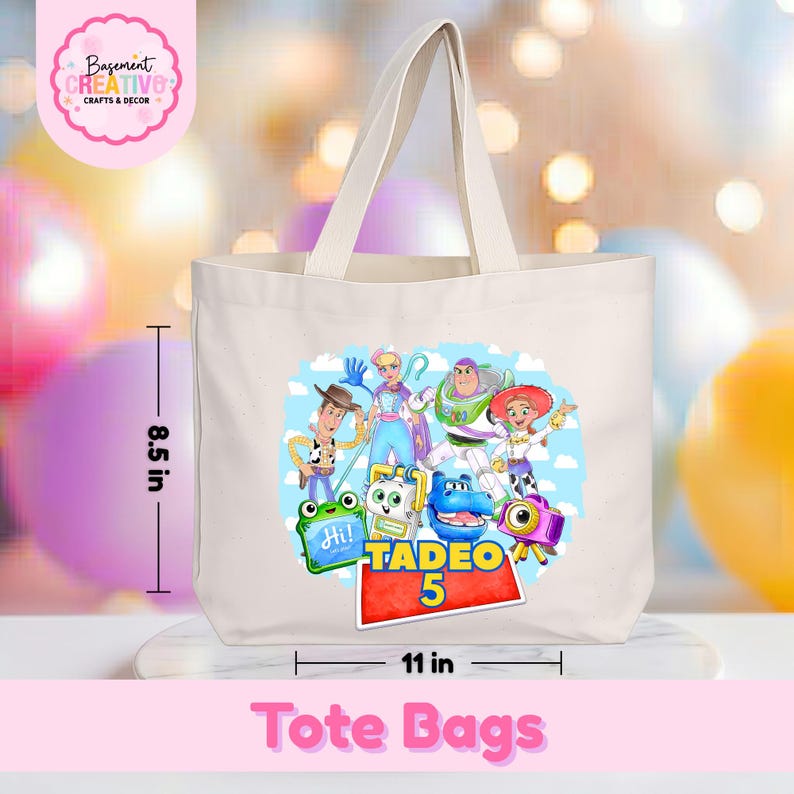 May include: A cream-colored canvas tote bag featuring a colorful graphic of various animated characters and the text Tadeo 5. The bag measures 11 inches wide by 8.5 inches tall, with two top handles and a rectangular base for carrying items.