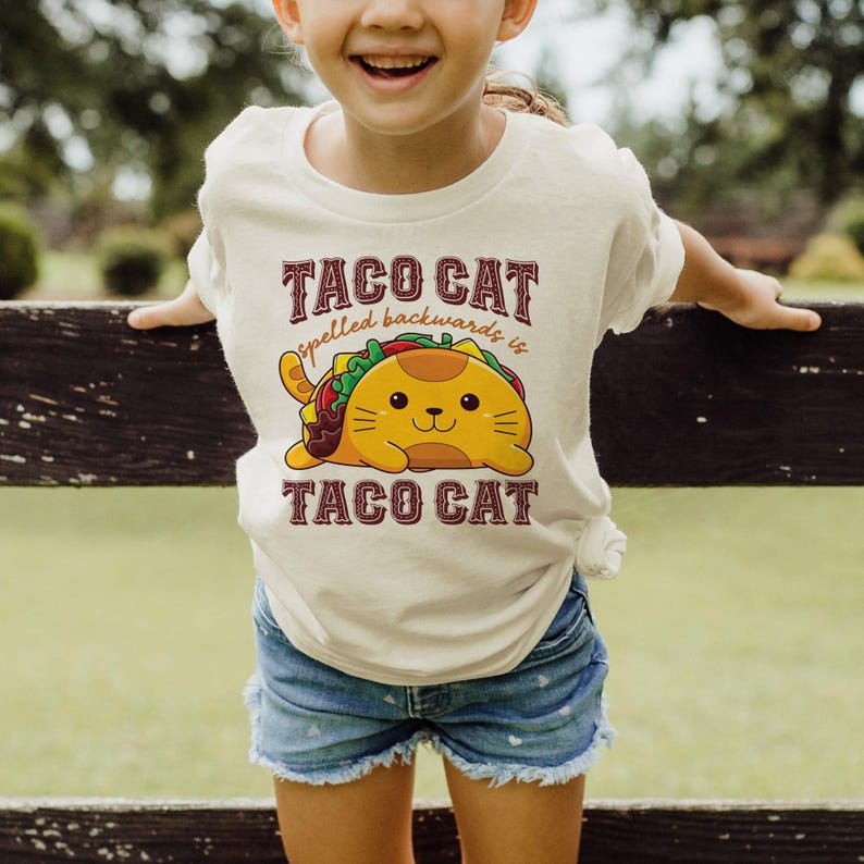 a little girl wearing a taco cat t - shirt