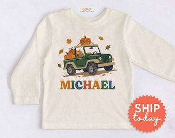 May include: A cream-colored long-sleeve shirt featuring a graphic of a green off-road vehicle carrying orange pumpkins on its roof and in the back. The name MICHAEL is printed in large, multi-colored letters below the vehicle illustration.