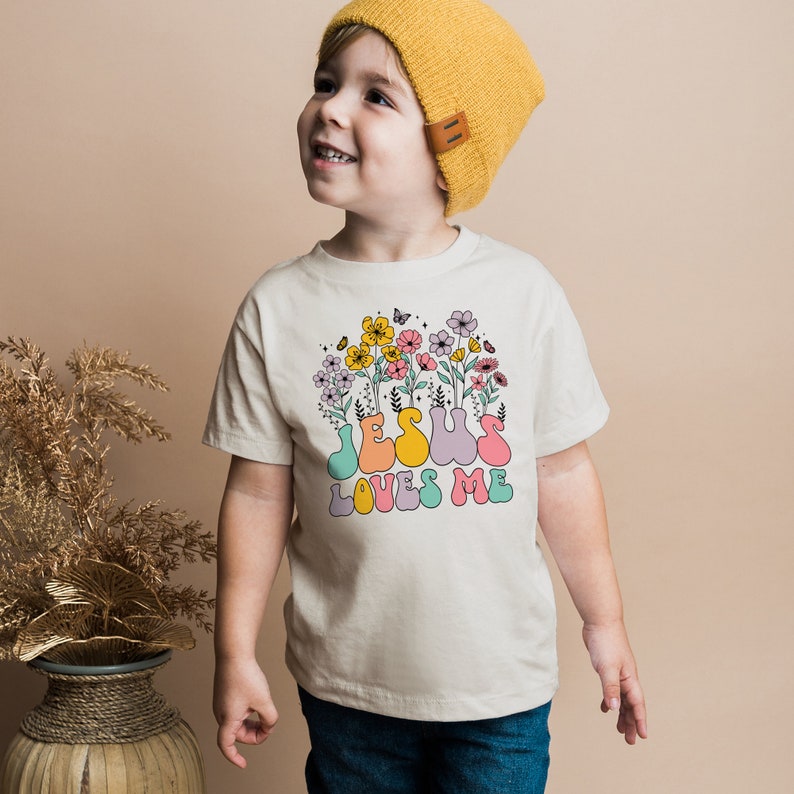 a little boy standing next to a vase with flowers on it