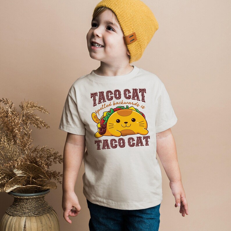 a young boy wearing a taco cat t - shirt