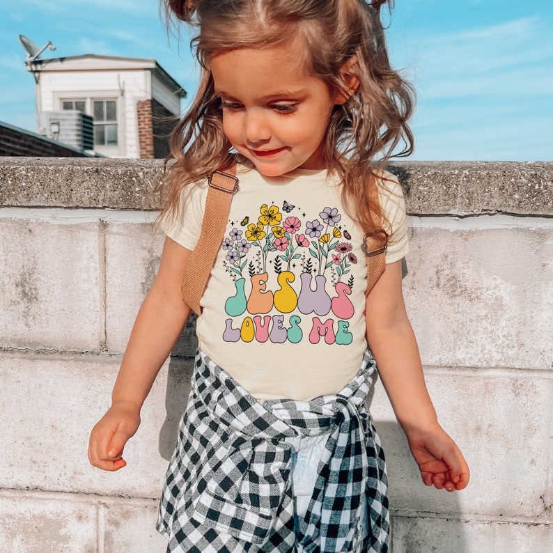 a little girl standing on top of a cement wall