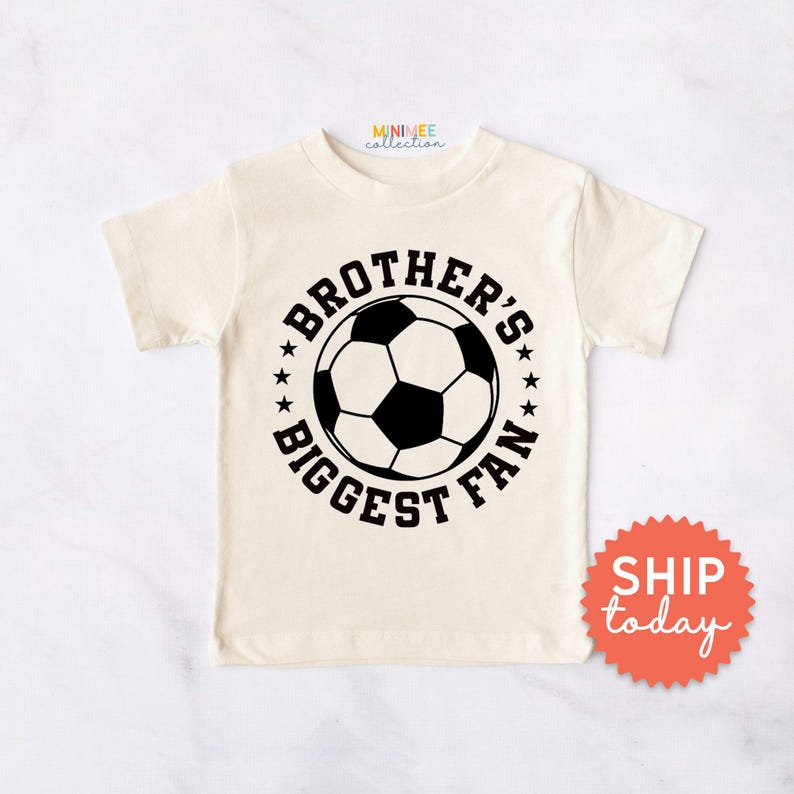 A white t-shirt with a graphic design featuring a soccer ball and the text "BROTHER'S BIGGEST FAN" printed on it.