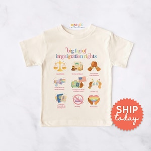 May include: Cream-colored t-shirt with the text "big fan of immigration rights" and various related illustrations. The shirt features images of scales, hands clasped, a megaphone, a passport, and a rainbow heart.