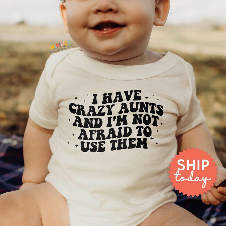 a baby laying on a bed wearing a t - shirt that says i have crazy