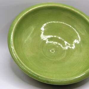 May include: A green ceramic bowl with a smooth, glossy finish. The bowl is empty and has a slight curve to the rim.