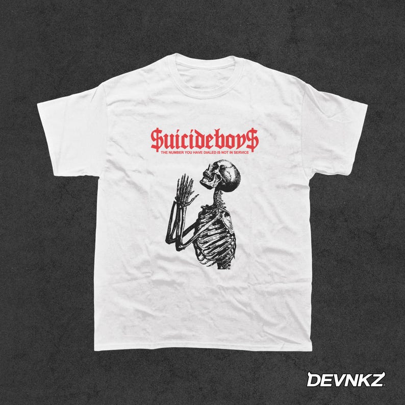 May include: White t-shirt with a black and white image of a skeleton praying. The text "Suicideboys" is printed in red above the image and the text "The number you have dialed is not in service" is printed in red below the image.