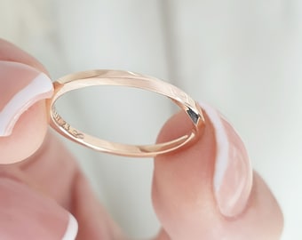 May include: A simple rose gold wedding band with a subtle shine. The band is inscribed with the number "1.23."