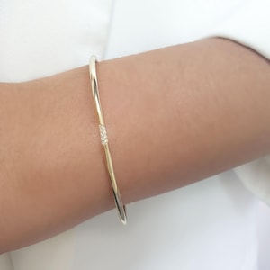 May include: A gold bangle bracelet with a small cluster of diamonds set into the band.