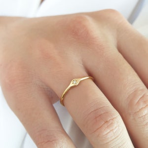 May include: A gold ring with a small diamond set in a star shape. The ring is thin and delicate.