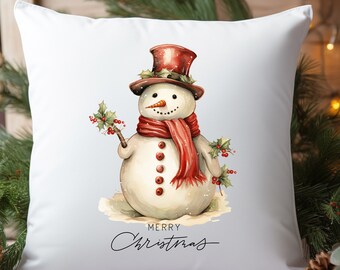 May include: White throw pillow with a watercolor illustration of a snowman wearing a red hat and scarf. The snowman is holding a branch with holly berries. The text "Merry Christmas" is written below the snowman.
