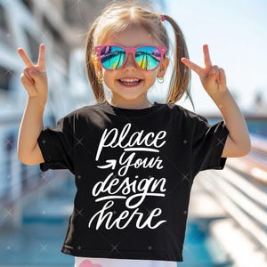 May include: A black t-shirt with the text "place your design here" in white. A young person is wearing the shirt and smiling while making a peace sign with both hands.