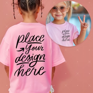 May include: Pink t-shirt with the text "place your design here" in black script on the back. A smaller version of the shirt is shown in a circle, with the same text on the front.