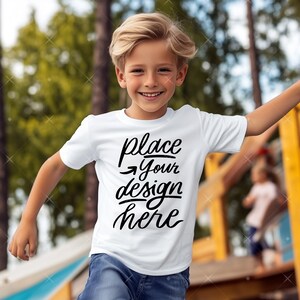 Może przedstawiać: Biała koszulka z napisem "place your design here" czarnymi literami. Młoda osoba nosi koszulkę i uśmiecha się.