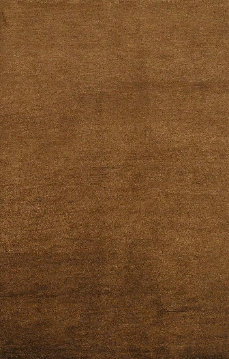May include: A solid brown rug with a textured surface. The rug has a warm, earthy tone, and the fibers create subtle variations in color. This rug is suitable for living rooms, bedrooms, or entryways.