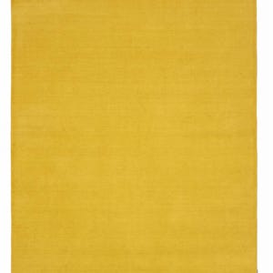 Puede incluir: Una alfombra rectangular de un color amarillo mostaza sólido y vibrante. La alfombra presenta una textura de pelo denso y uniforme en toda su superficie, con bordes rectos y limpios y una apariencia monocromática consistente en todo el diseño.