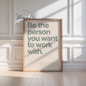 Könnte beinhalten: Ein rechteckiger Holzrahmen mit einem beigen Poster, das den salbeigrünen Text trägt: Be the person you want to work with. Darunter steht in kleinerer Schrift: Show up with integrity, communicate with clarity, and treat others with the respect you expect in return. Set the standard through your actions and create the kind of energy that inspires collaboration and trust.