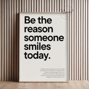 Könnte beinhalten: Ein rechteckiges gerahmtes Wandbild mit weißem Hintergrund und fettgedrucktem schwarzem Text: Be the reason someone smiles today. Darunter steht in kleinerer Schrift: Kindness costs nothing, yet it can change everything.