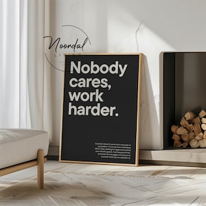 Puede incluir: Arte de pared enmarcado en negro con el texto blanco "Nobody cares, work harder". La obra de arte se exhibe en un salón moderno. Texto adicional en la parte inferior.