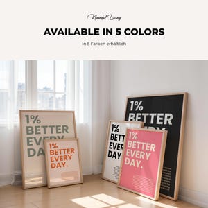 Five framed motivational posters leaning against a wall in a room with a wooden floor, featuring the text 1% better every day in various color schemes.