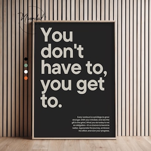Könnte beinhalten: Ein gerahmter Schwarz-Weiß-Druck mit dem Text "You don't have to, you get to." Der Druck enthält ein motivierendes Zitat über Bewegung und persönliches Wachstum. Der Rahmen ist neutralfarben, und der Hintergrund ist eine Holzwand.